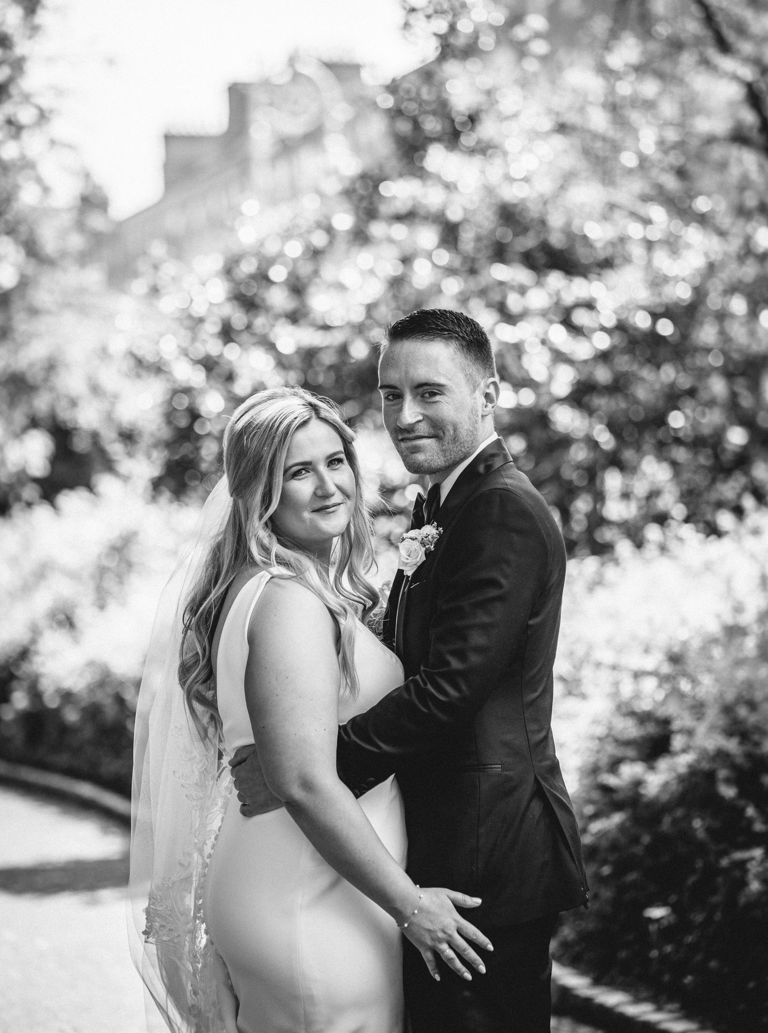A romantic black and white portrait of a couple embracing during their wedding day.