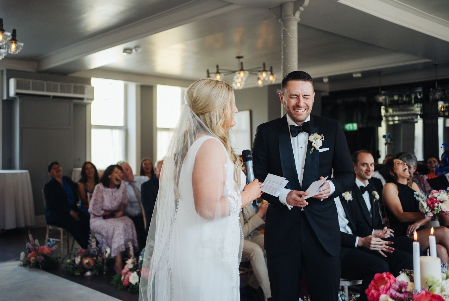 A wedding couple exchanges rings during their indoor ceremony.