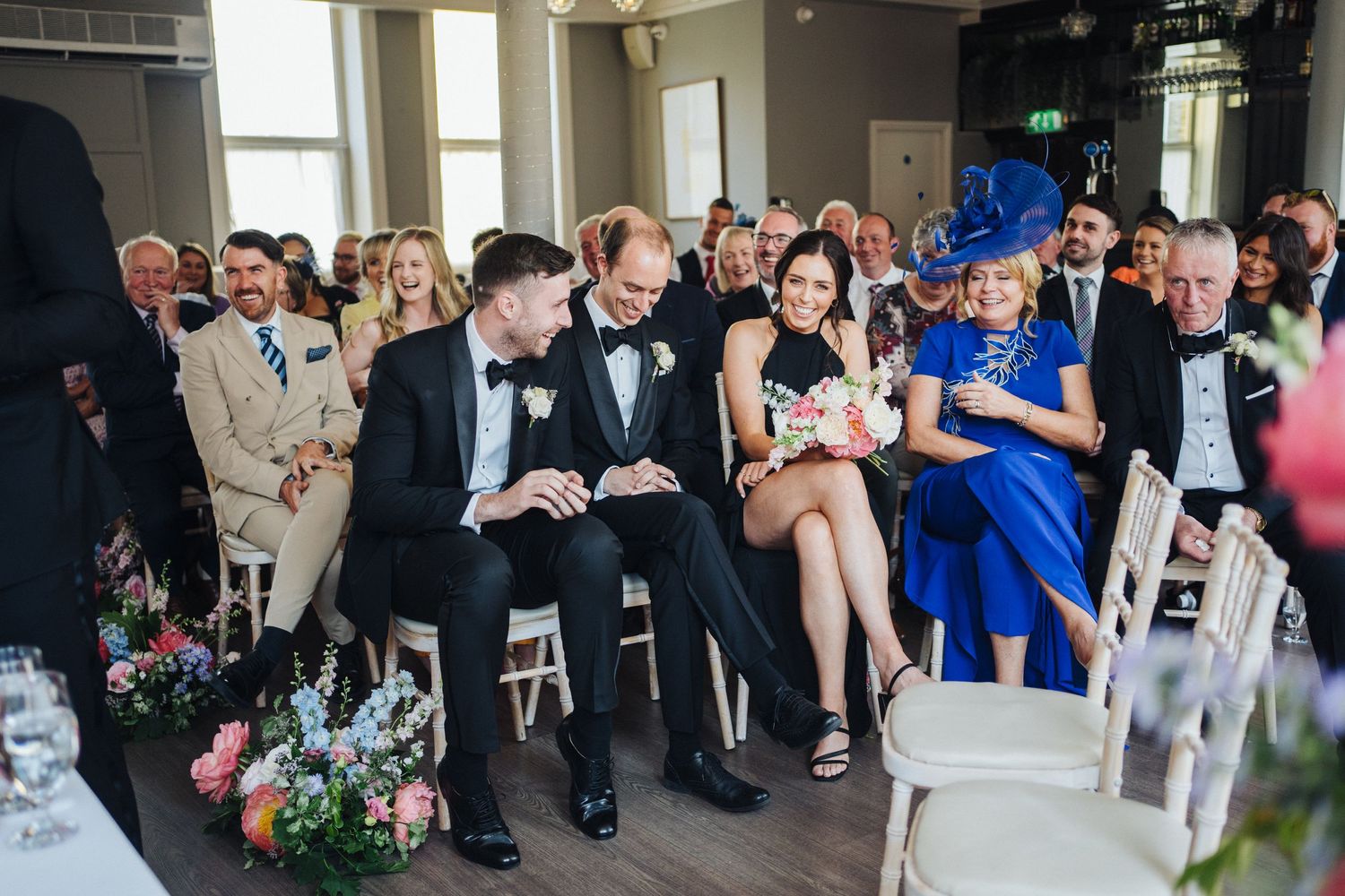 Wedding guests seated in rows at an indoor ceremony venue.