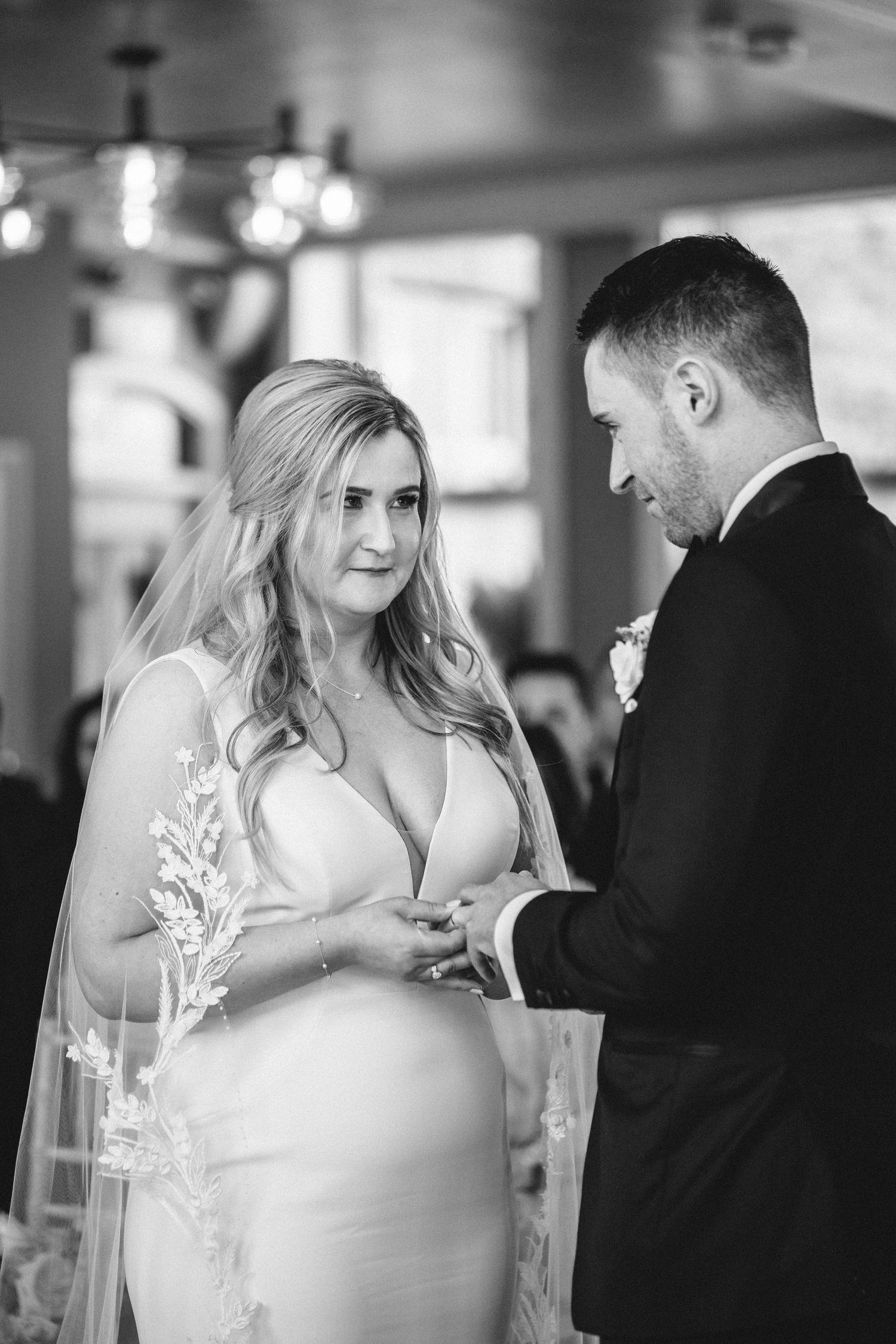 A wedding ceremony captured in black and white as the couple exchanges rings during their intimate moment.