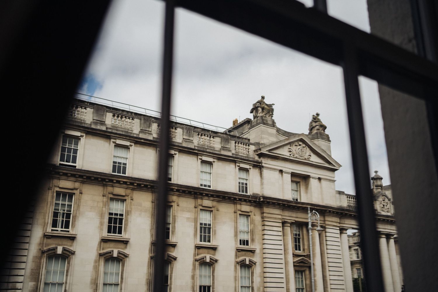 Classical architecture of a grand stone building viewed through a window frame.