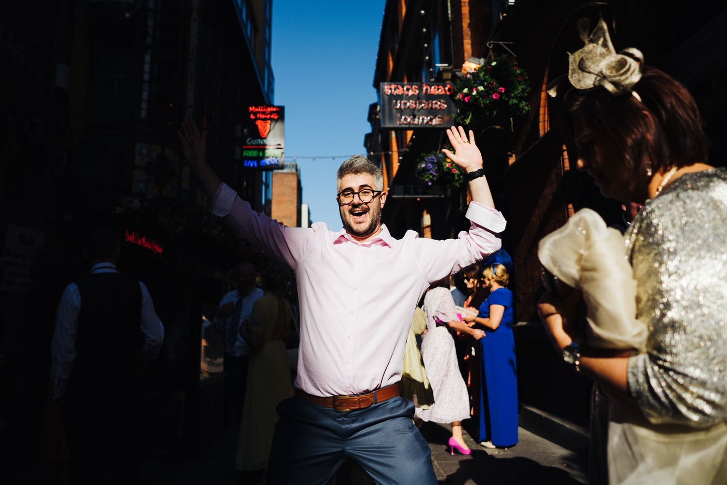 A bright outdoor celebration scene with guests dancing and celebrating in sunlight.