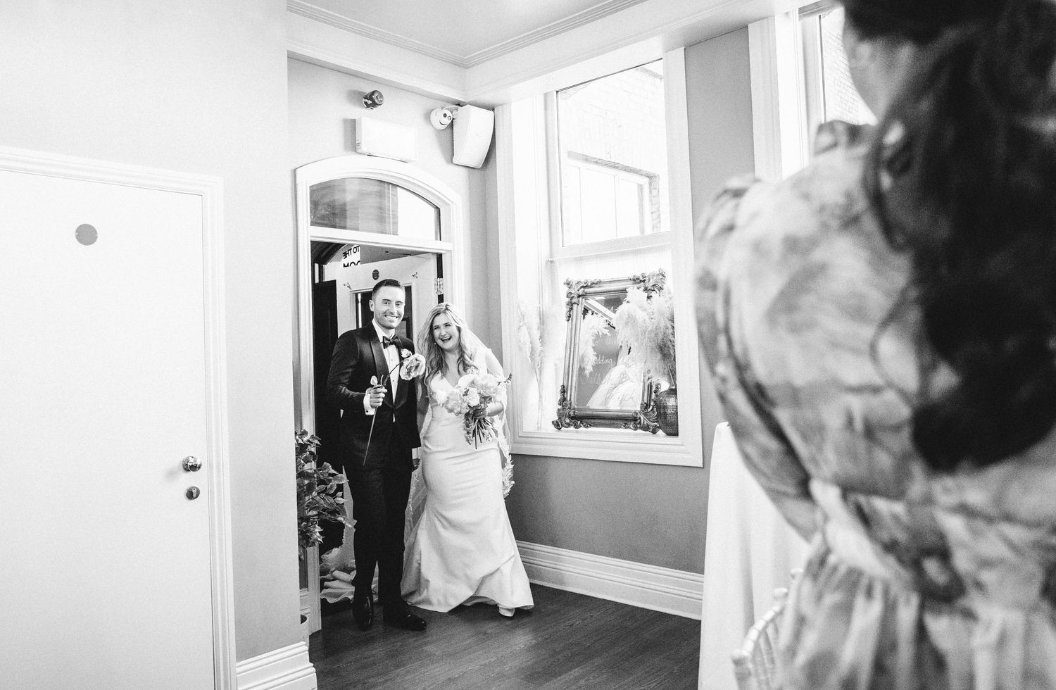 Black and white photo of wedding preparation moments in a bright interior hallway.