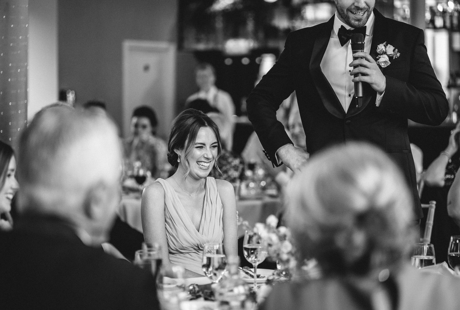 A formal reception speech being given while guests listen attentively at decorated tables.