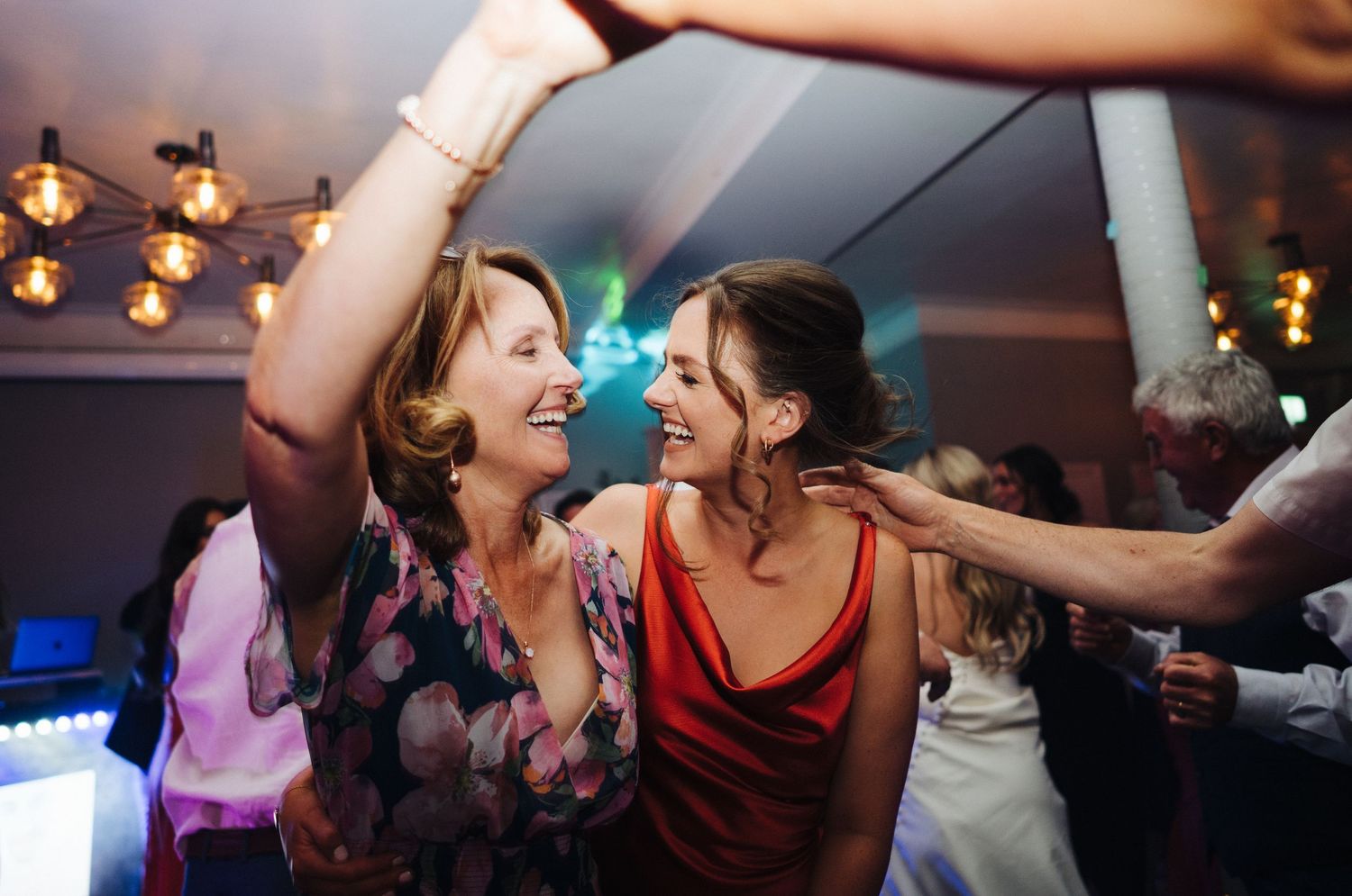Joyful guests dancing together under warm lighting at a wedding reception.
