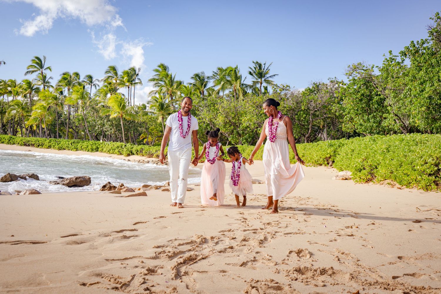 Family walking together on a tropical beach path lined with palm trees.
