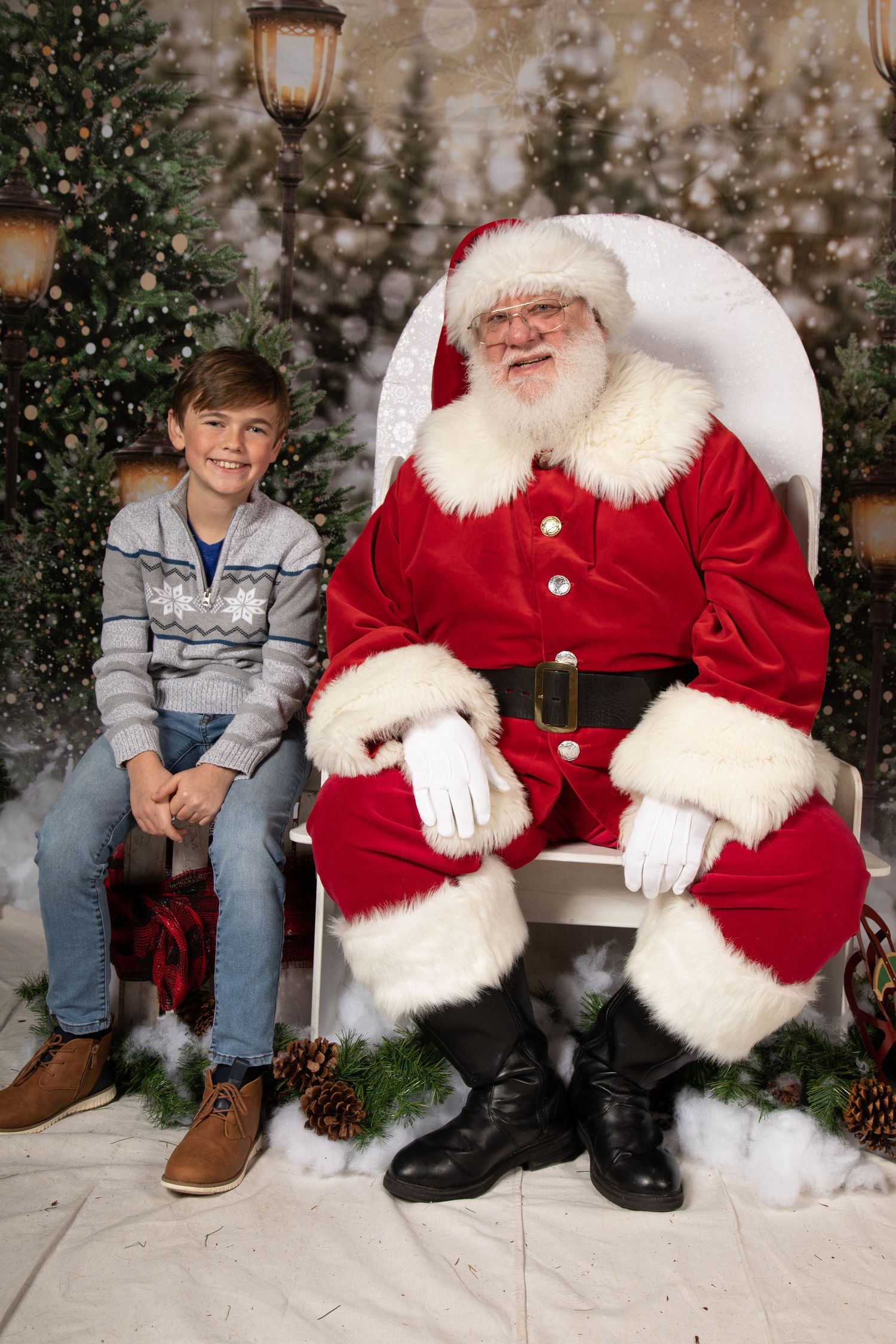 Holiday portrait in front of decorated Christmas tree with glowing lantern and snowy backdrop.