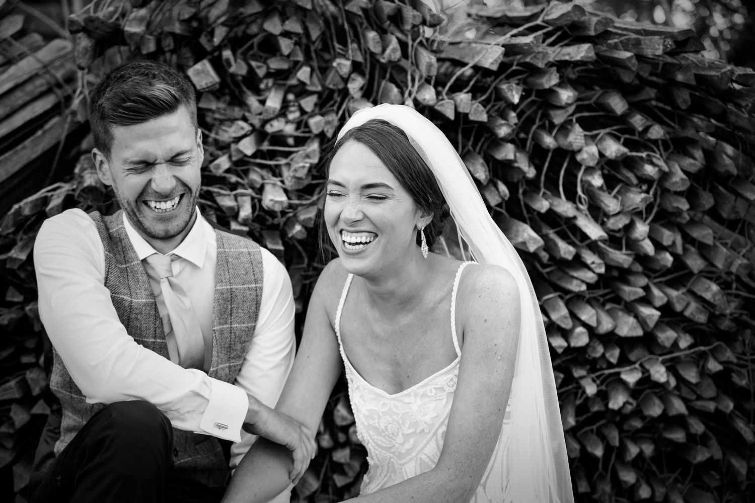 Black and white candid wedding moments captured against natural foliage.