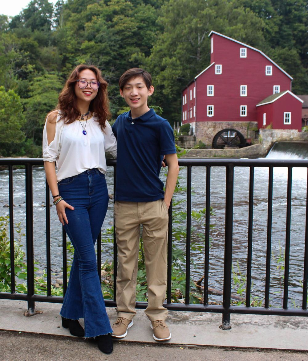 Two people standing at railing with historic Red Mill and rushing water in background.