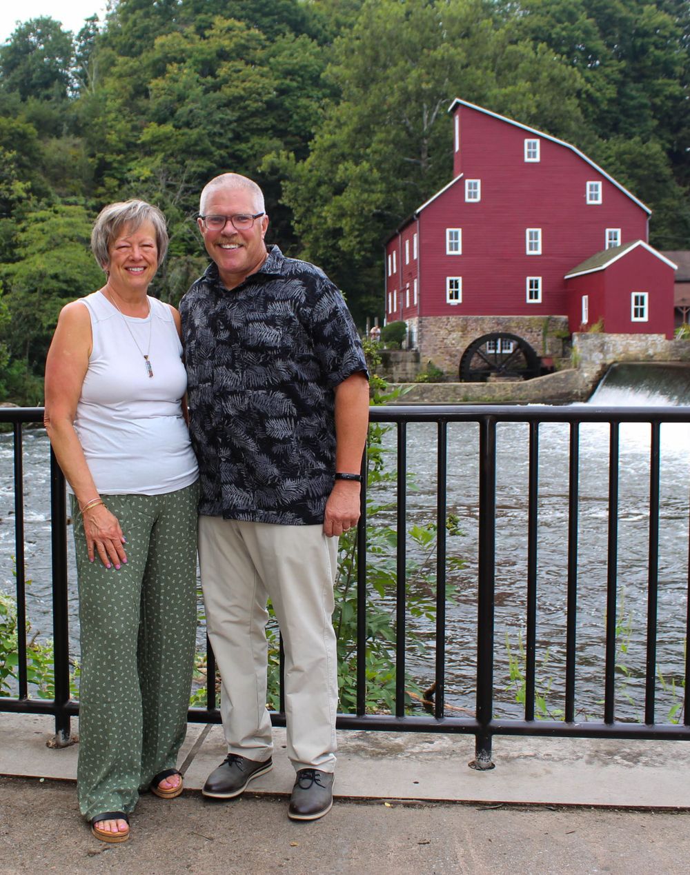 Couple posing at viewing area overlooking the Red Mill Museum and waterfall.