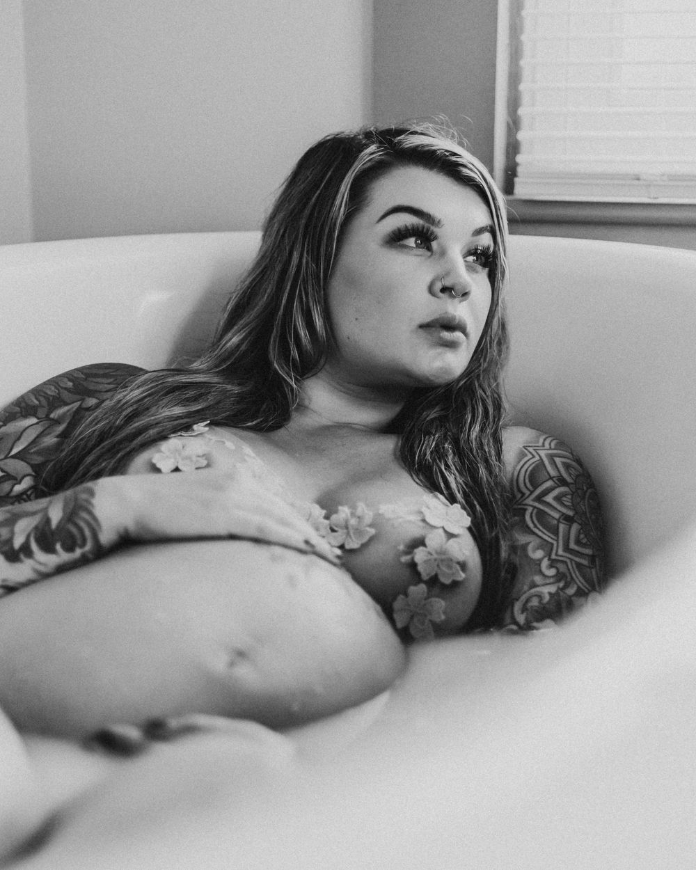 Black and white portrait in bathtub highlighting pregnancy silhouette.