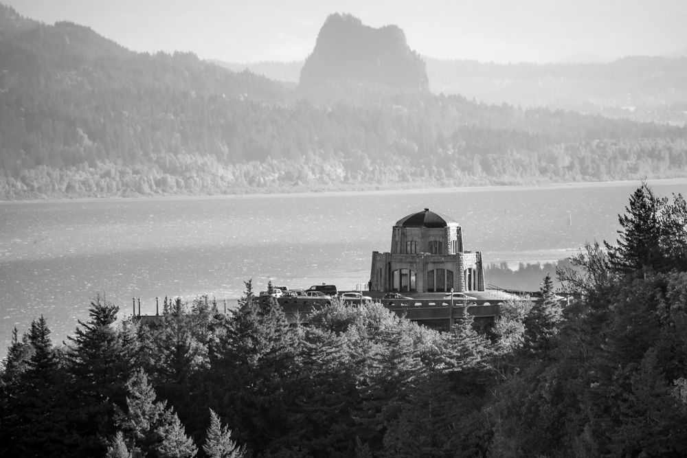 Historic Vista House overlooking the Columbia River Gorge in a moody black and white landscape.
