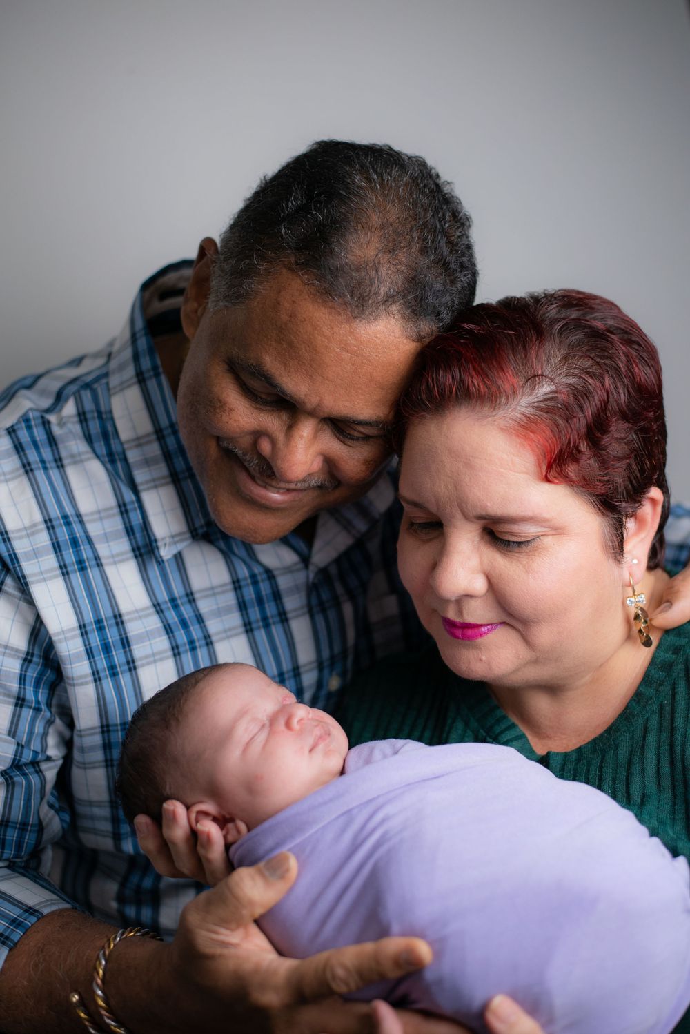 Loving family moment as couple holds their newborn wrapped in purple.