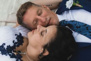 Bride and groom lying close together, eyes closed, sharing a peaceful intimate wedding portrait moment.