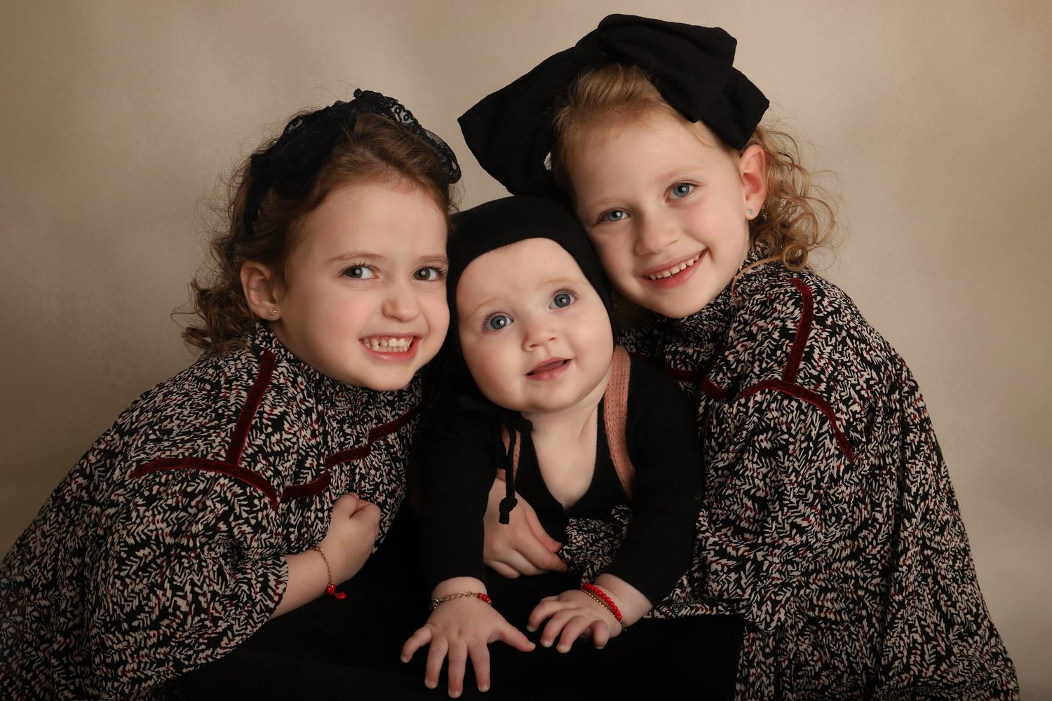 Professional studio portrait featuring coordinated floral dresses against neutral backdrop.
