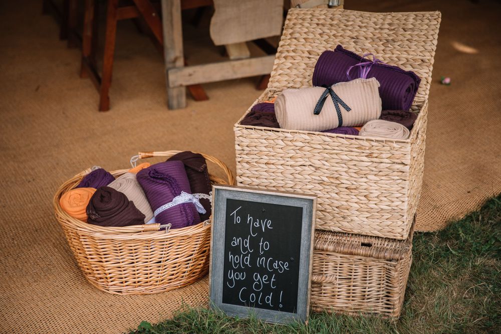 Wicker baskets with purple blankets and a chalkboard sign displayed on burlap.