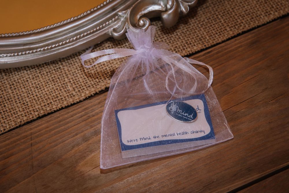 Small organza favor bag with tag sitting on wooden surface with burlap accent.