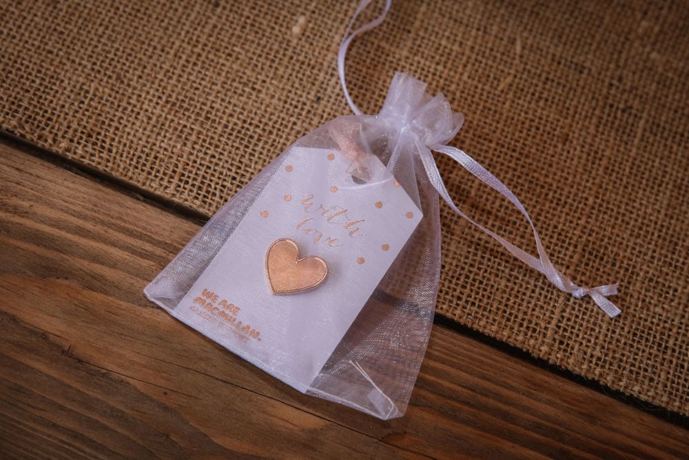 Delicate wedding favor bag with heart tag on rustic wooden surface.