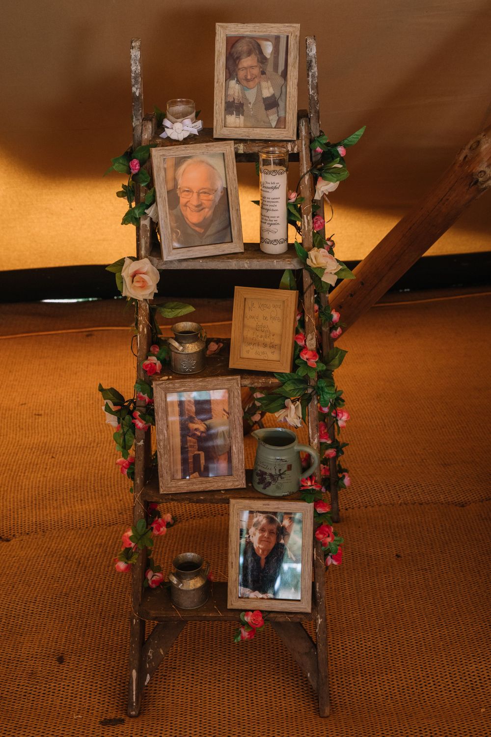 Decorative ladder display with photographs and floral garland in warm lighting.