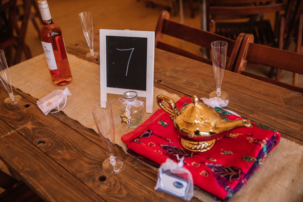 Table setting with red napkin, chalkboard number sign, and wine glass on wooden surface.