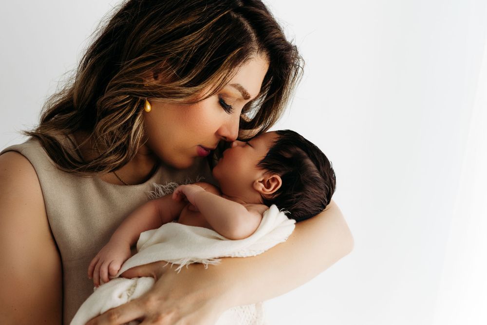 Intimate bonding moment between parent and infant in soft white studio lighting.
