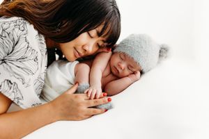 A tender moment between parent and sleeping infant on white bedding.
Rashinphotography-Nova photographer- DMV DC