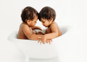 Two small children sharing precious moment together in white bathtub.