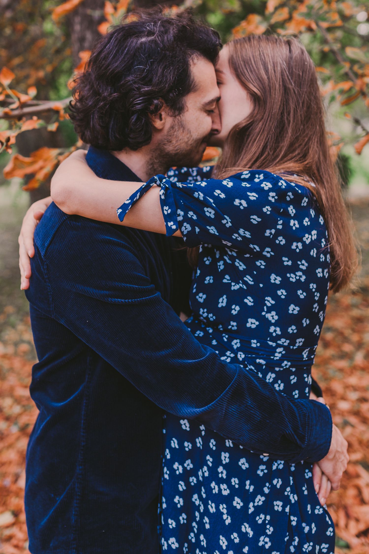 A romantic moment shared between a couple among autumn leaves.