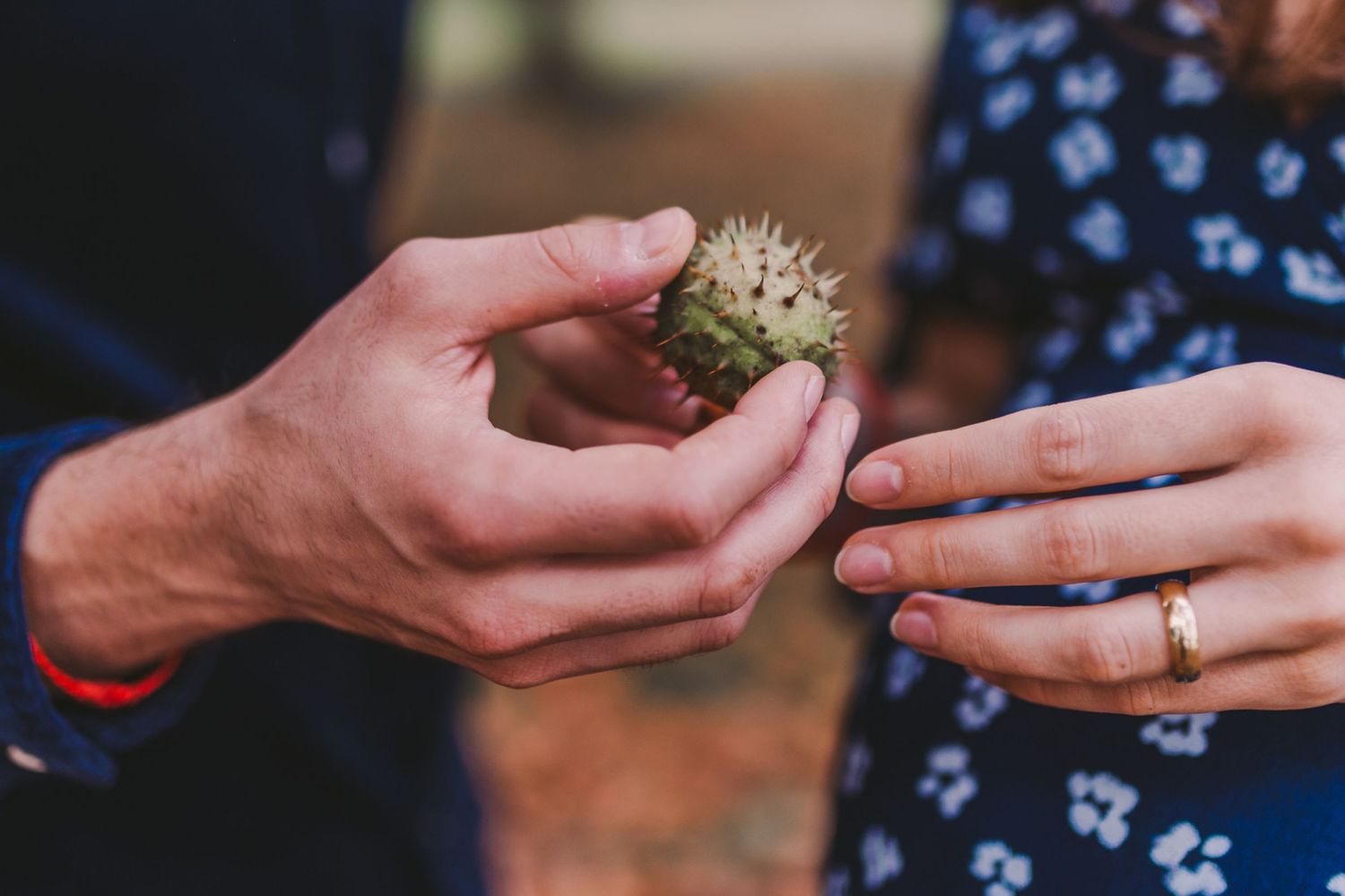 Close-up of hands holding a small natural object during an outdoor photoshoot.