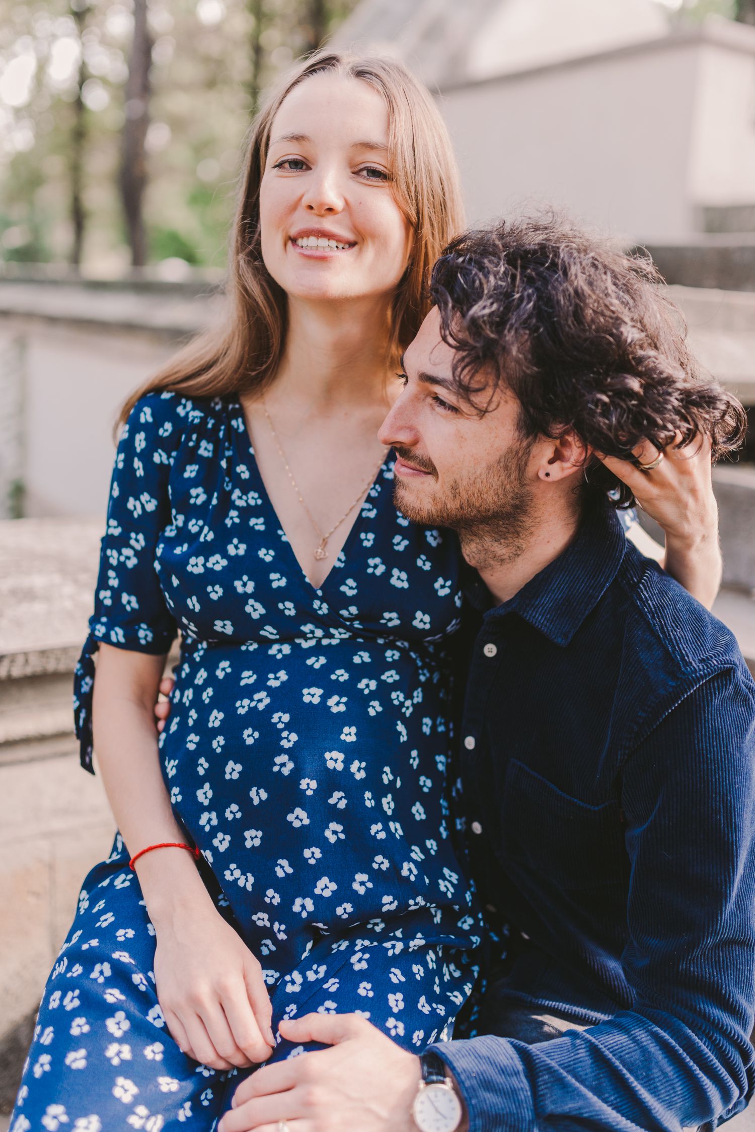 A couple shares an intimate moment on outdoor steps while wearing coordinating blue outfits.
