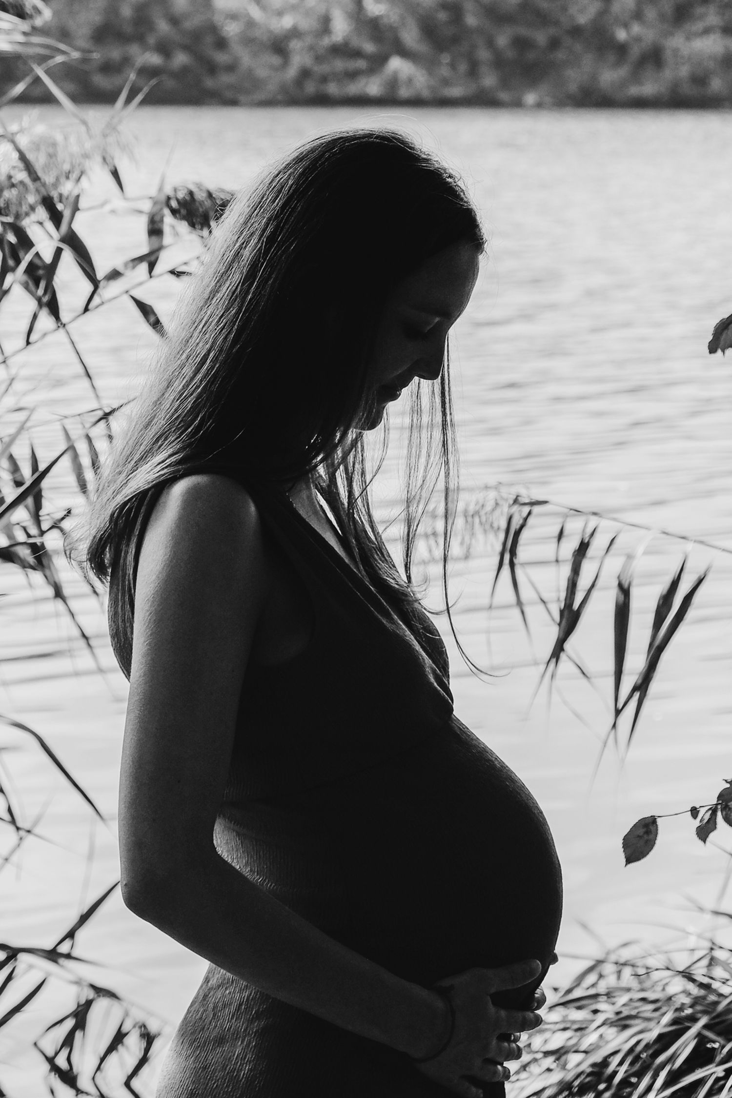 Silhouetted maternity photos by water showcase expecting mother's profile.