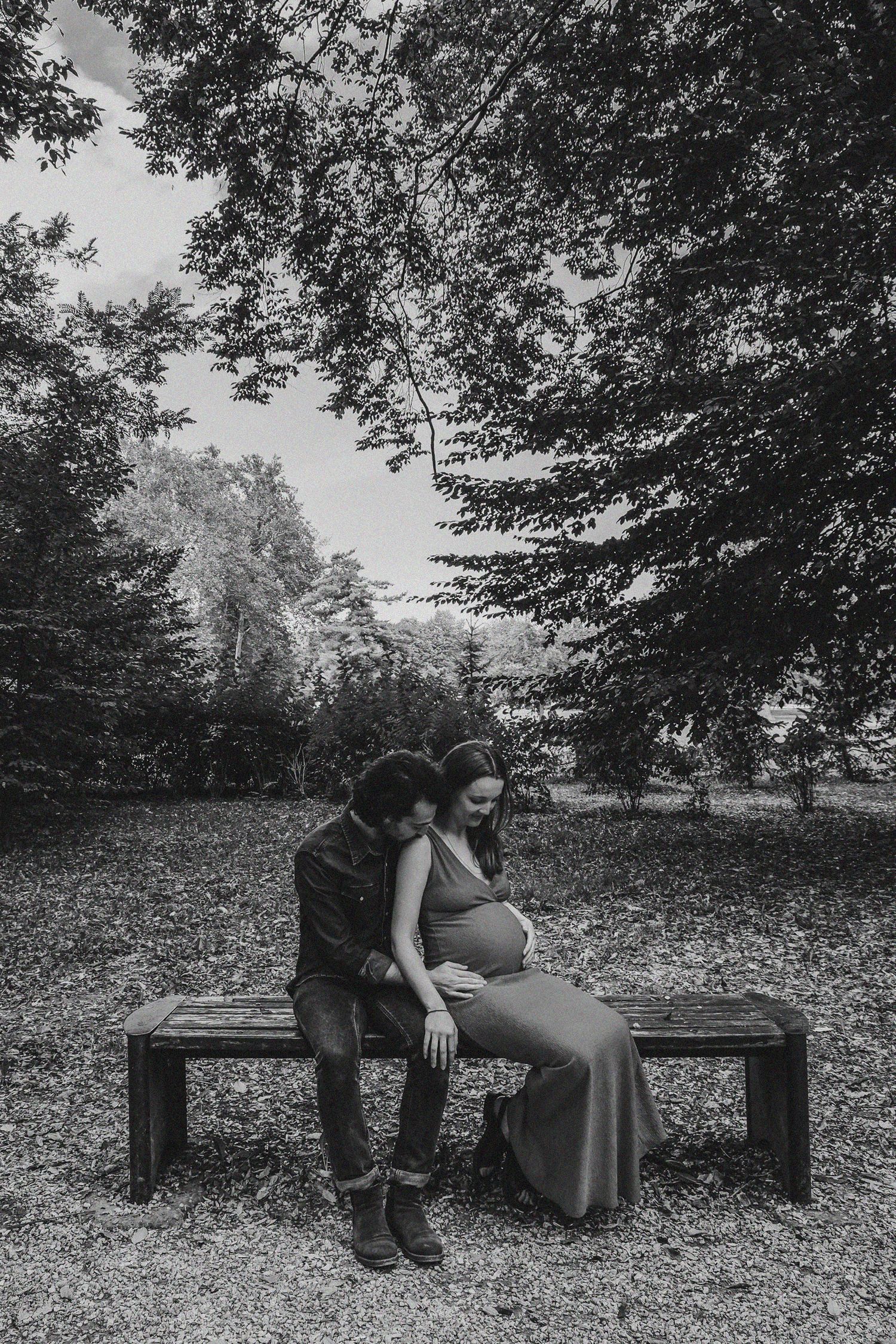 Black and white photographs of a couple sharing quiet moments on a bench surrounded by fallen leaves.