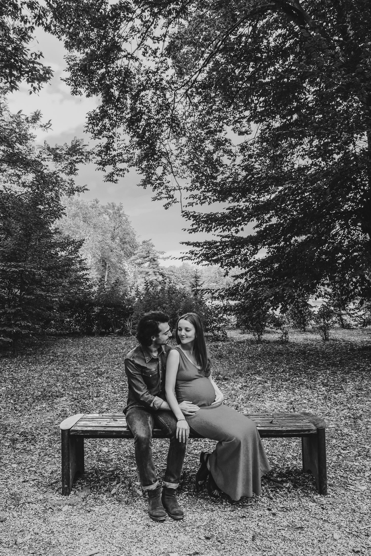 Black and white photos of a couple sitting together on a wooden bench in a park setting.