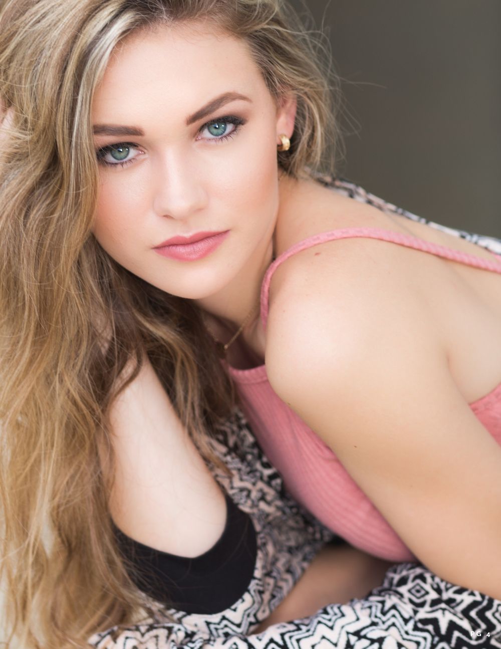 Soft glamour portrait with natural makeup and blonde hair against neutral background.