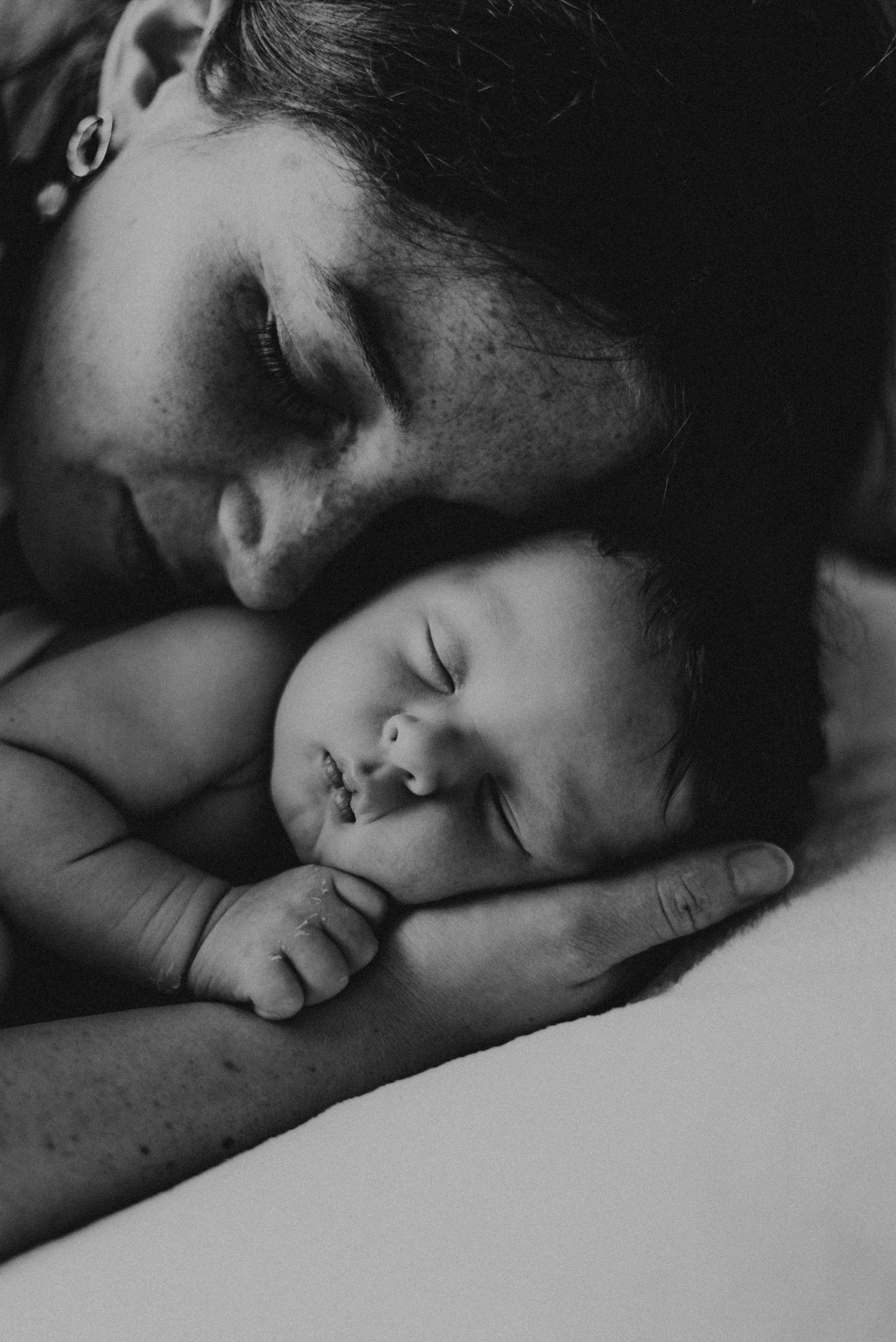 Artistic black and white capture of tender moment with sleeping baby.