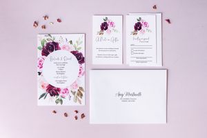 Wedding invitation suite with floral design featuring purple and pink watercolor flowers.