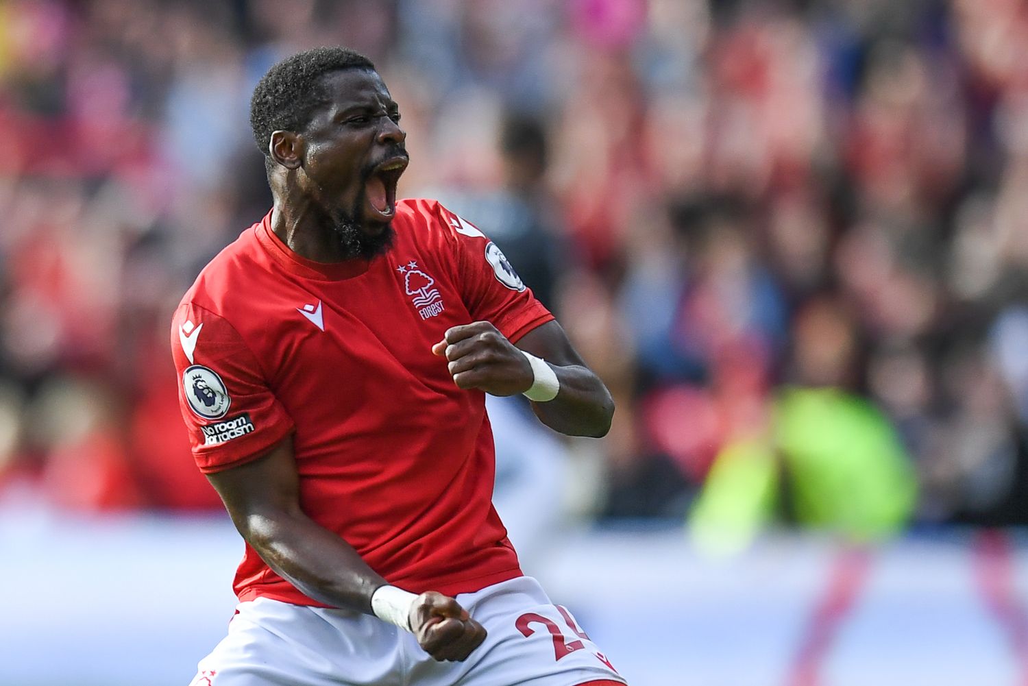 Soccer player in red jersey celebrates emotionally during match at stadium.