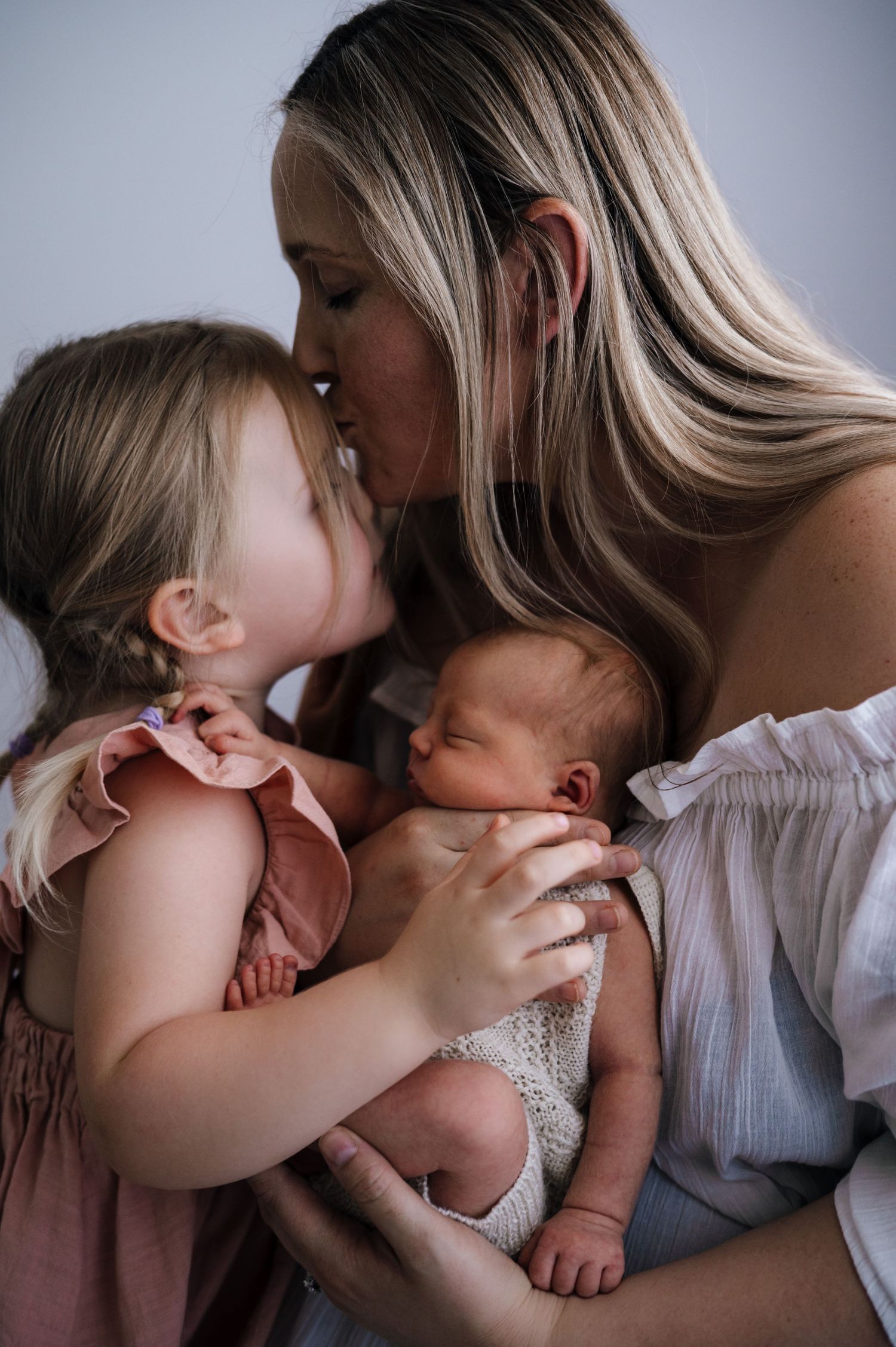 A tender family moment showing affection between mother and children in soft lighting.