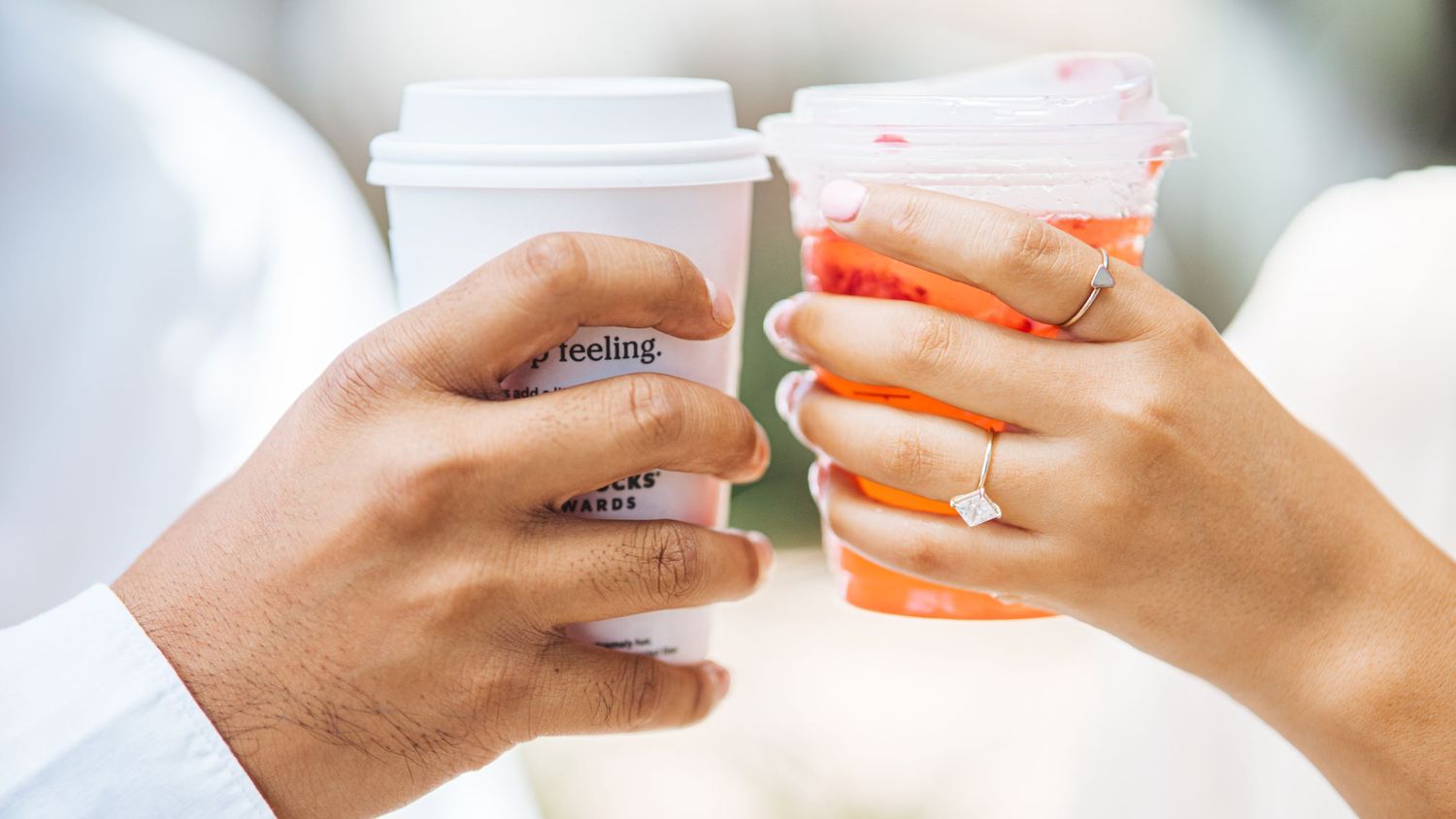 Close-up of hands holding coffee cups against a white background.