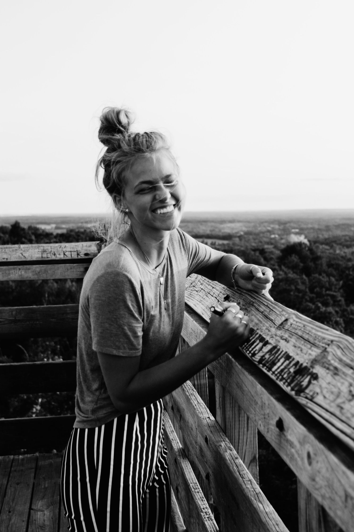 Candid moments of joy and laughter at a scenic wooden observation deck overlooking a forest landscape.