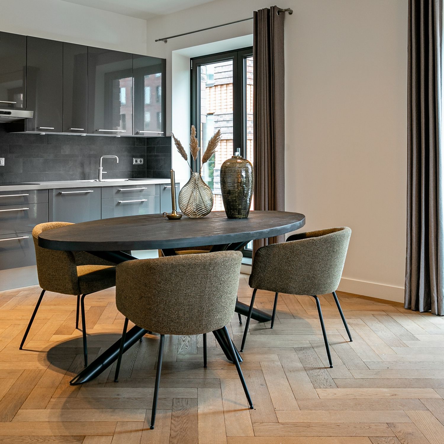 Oval black dining table with four dining chairs in a modern open kitchen