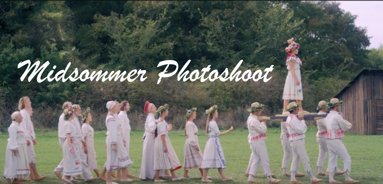 Group of dancers in white clothing performing in a grassy field.