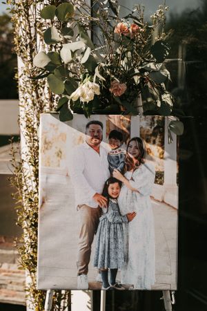 Beautiful floral arrangement with pink roses above a framed portrait displayed in natural sunlight.