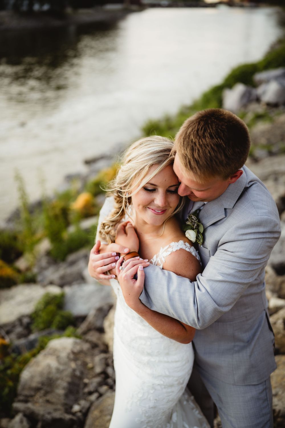 Romantic moment captured between newlyweds on rocky waterfront.