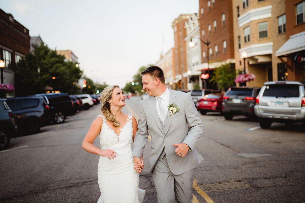 Newlyweds share a laugh while walking in downtown street setting.