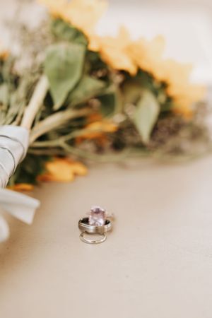 Wedding rings displayed artistically next to blurred floral decorations.