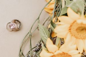 Wedding bands photographed with soft focus yellow sunflowers and greenery.