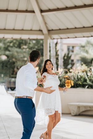 A couple shares a lighthearted moment during their wedding ceremony under a gazebo.