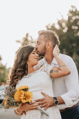 An intimate moment captured in golden hour light with sunflower bouquet.