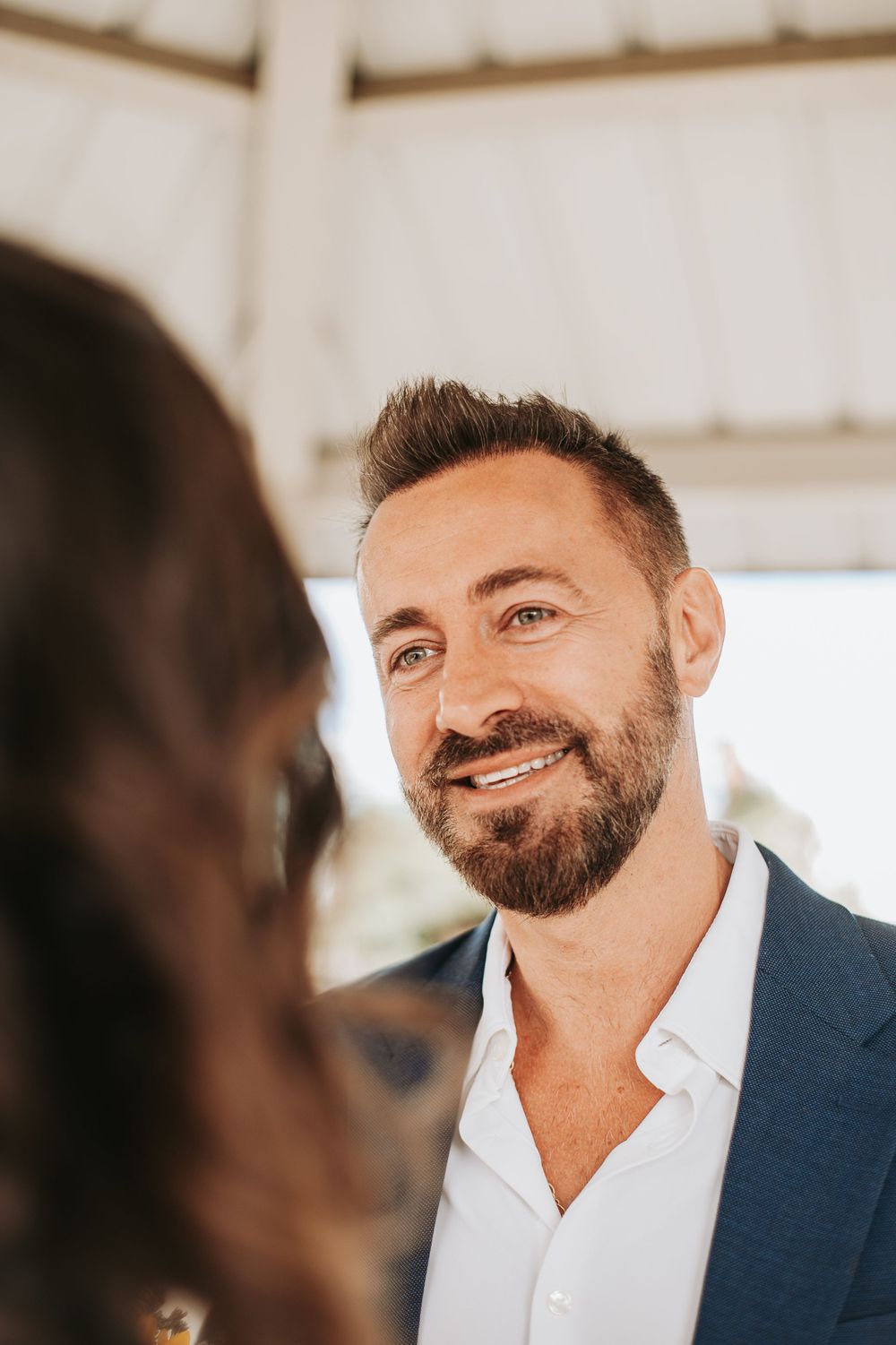 A close-up portrait in warm sunlight under a white gazebo.